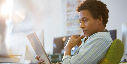 Ein Mann schaut nachdenklich auf sein Tablet und hält sich das Kinn